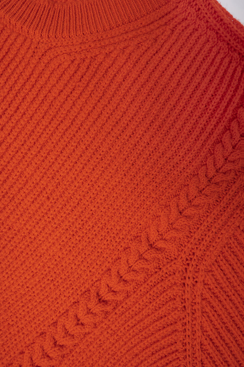 gros plan sur laine rouge tricotée avec des torsades