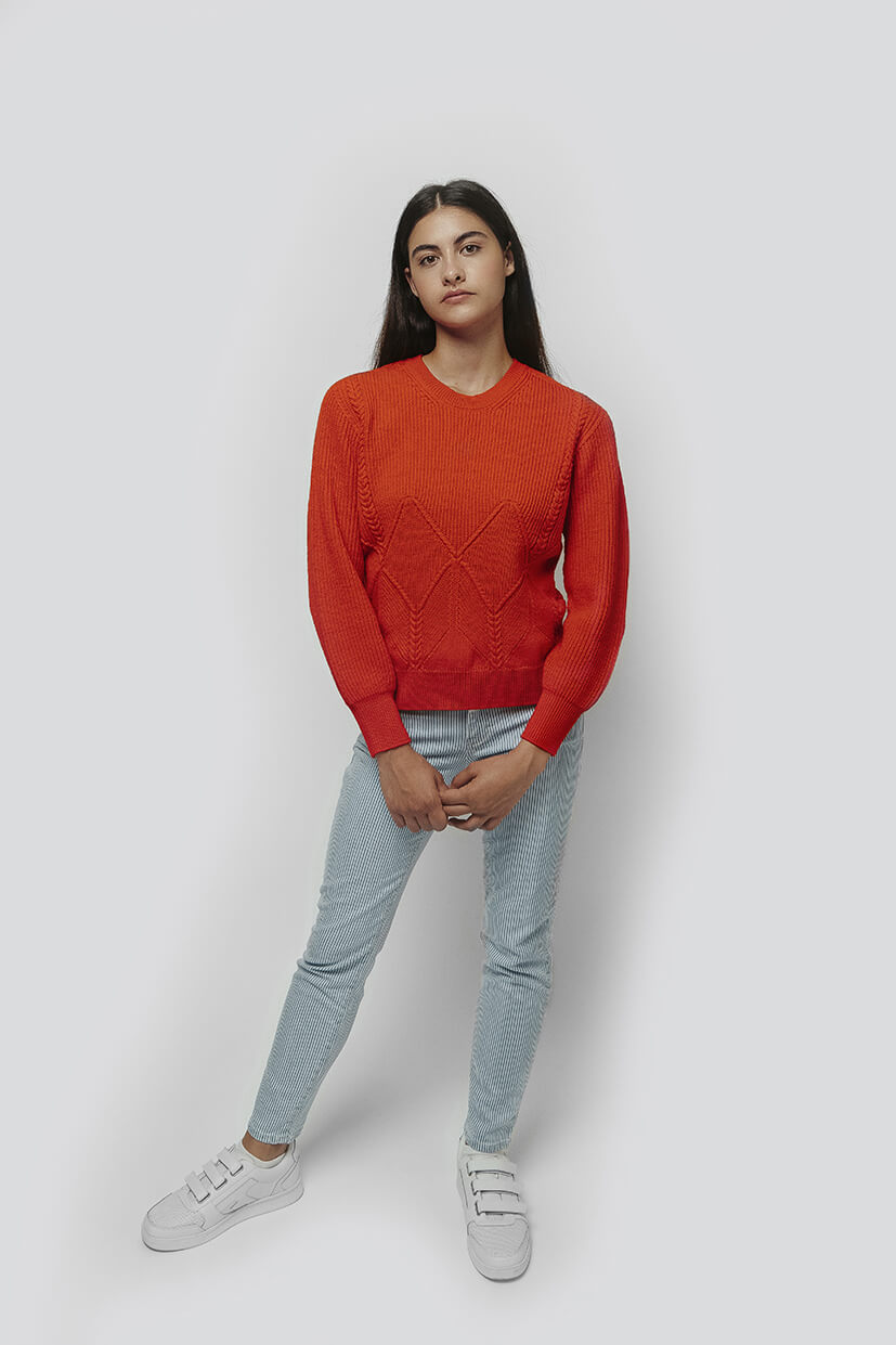 femme debout portant un pull en laine rouge et un jean