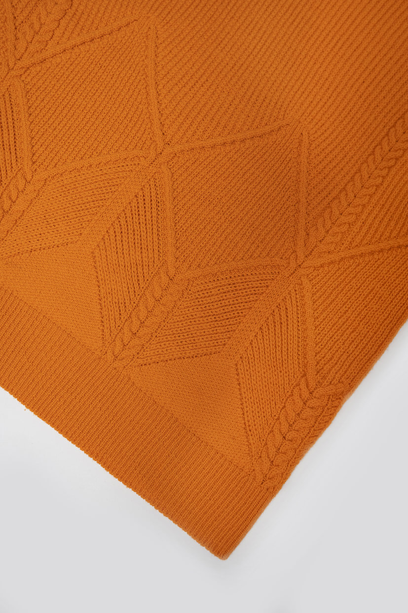 gros plan sur pull tricoté en laine orange avec jeu de points