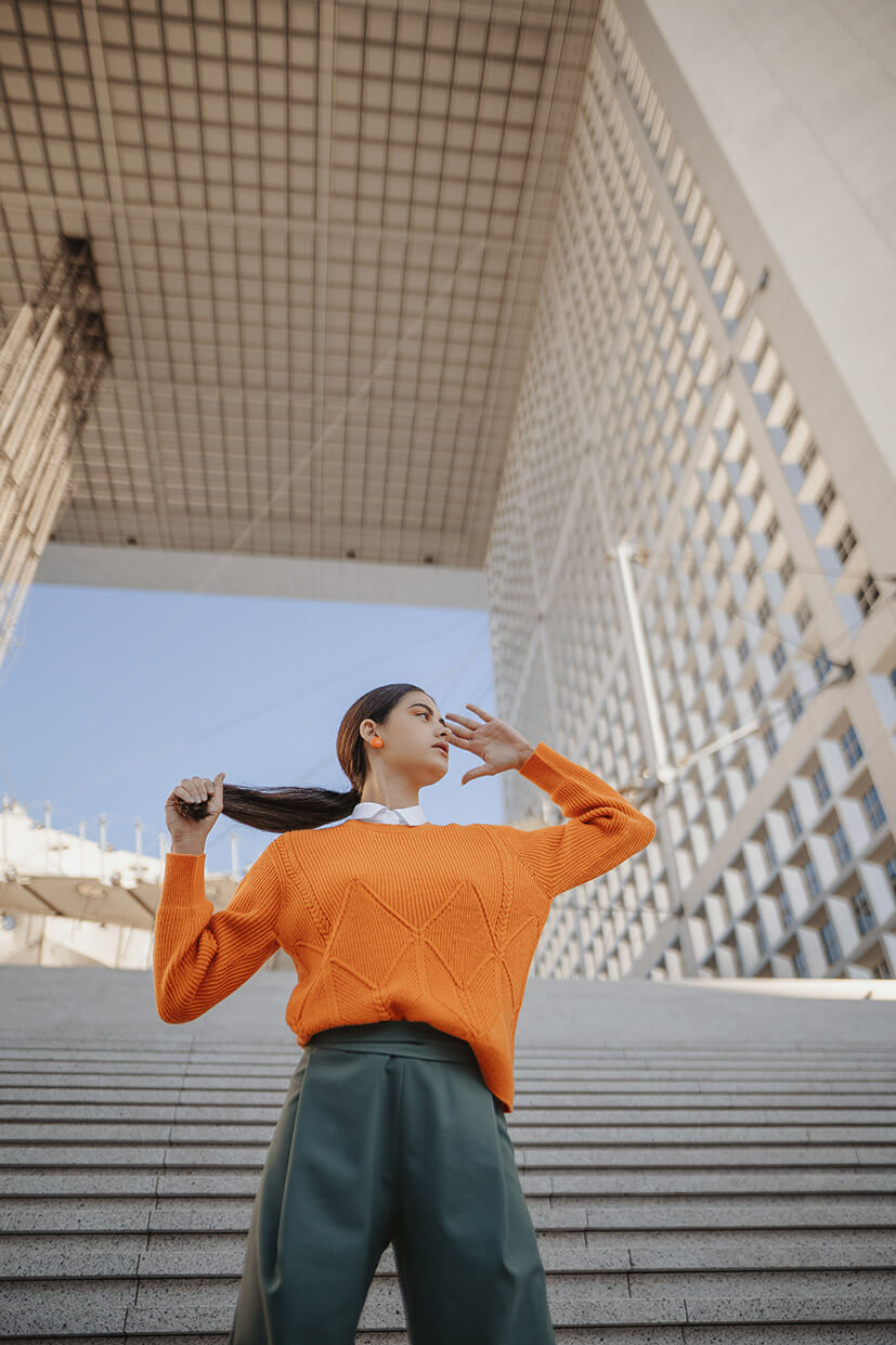 jeune femme portant un pull orange en laine à la Défense - Paris