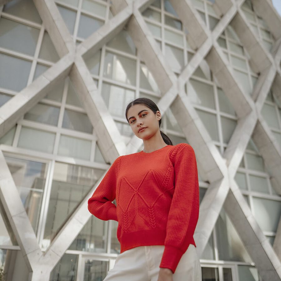 femme en pull rouge devant bâtiment La Défense Paris